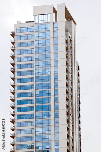 Residential building with blue windows on cloudy sky background