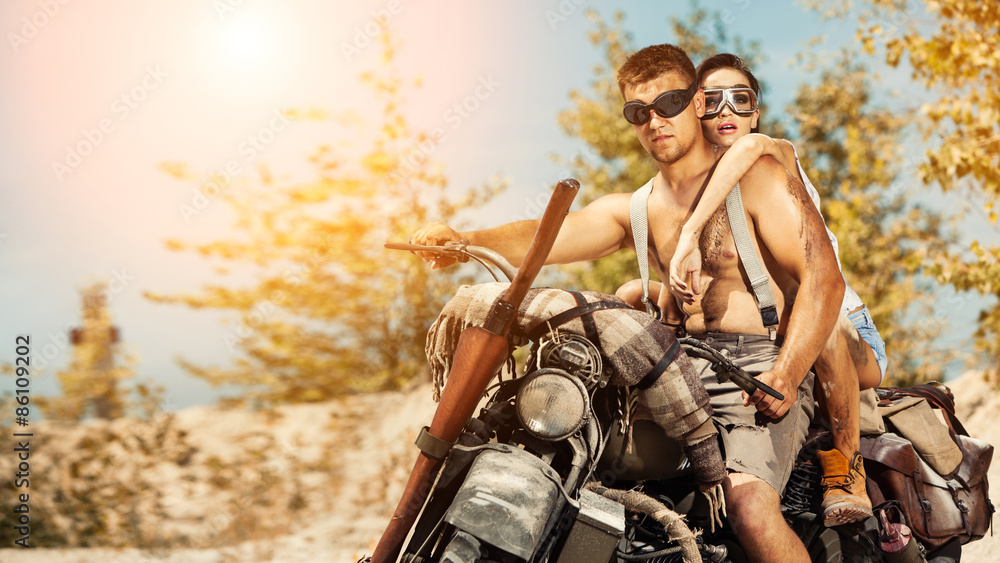 Obraz premium Sexy couple of bikers with guns on the summer background.