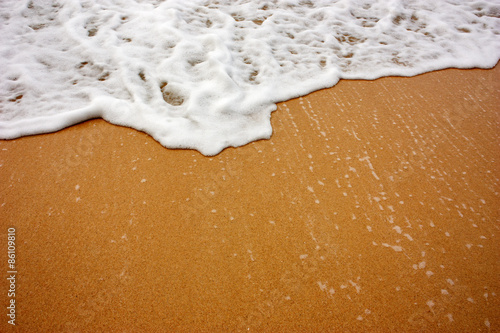 Sea wave with foam on sand
