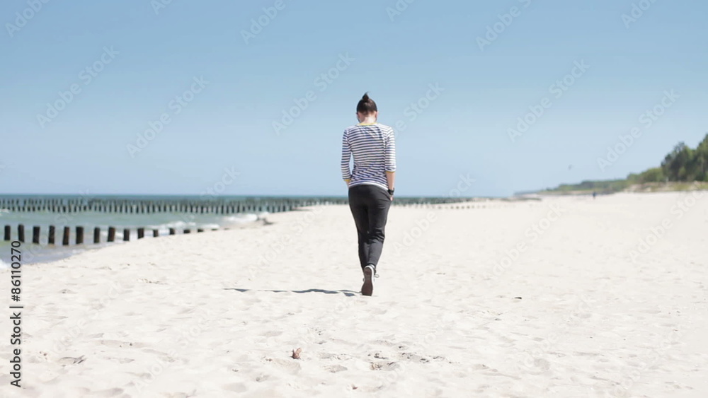 Woman walking on the beach, view from the back Woman walking on the beach, view from the back