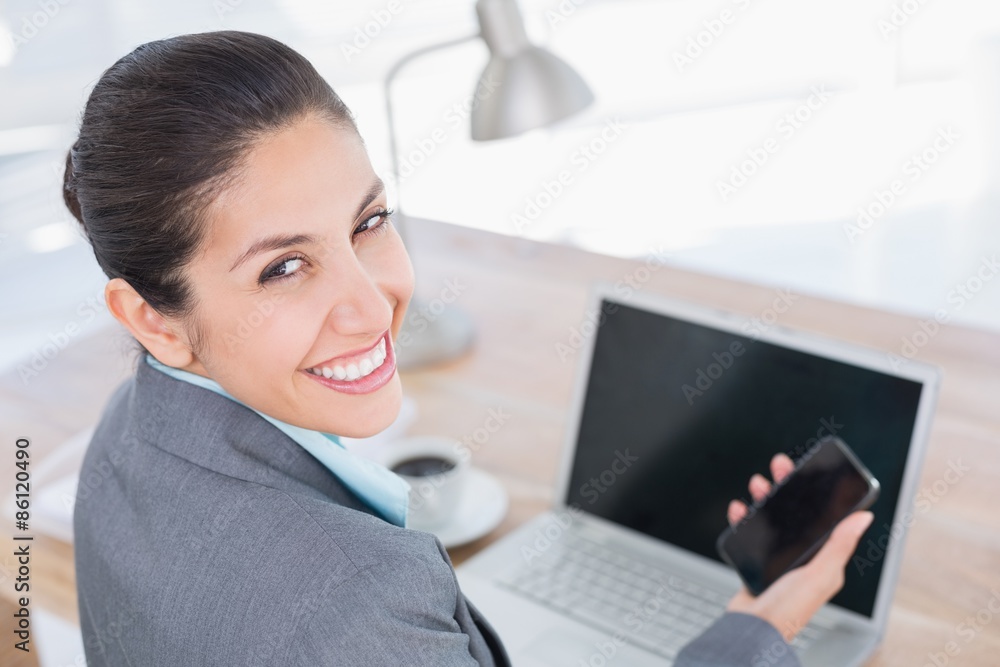 Smiling businesswoman looking at camera with her phone Smiling businesswoman looking at camera with her phone