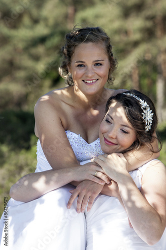 two brides smile and embrace in nature surroundings