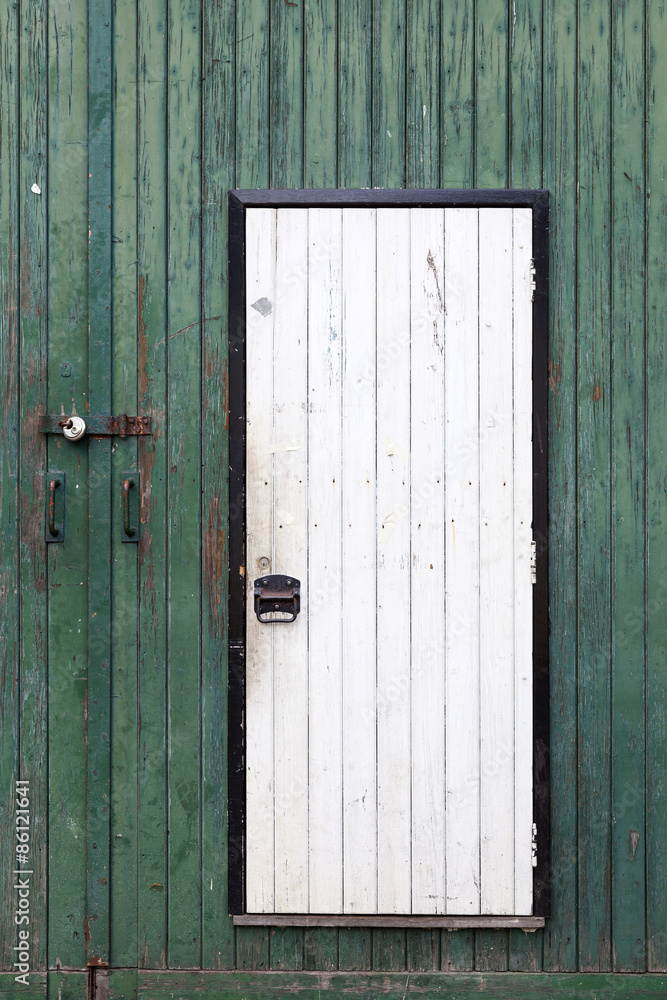 small white door in large green barn door
