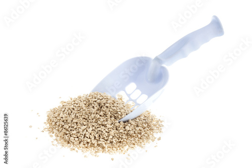 Plastic scoop for cleaning cat litter and a pile of filler on a