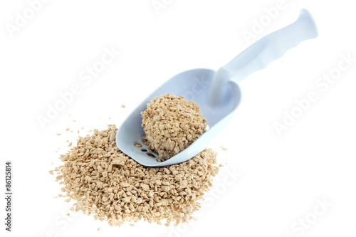 Plastic scoop for cleaning cat litter and a pile of filler on a