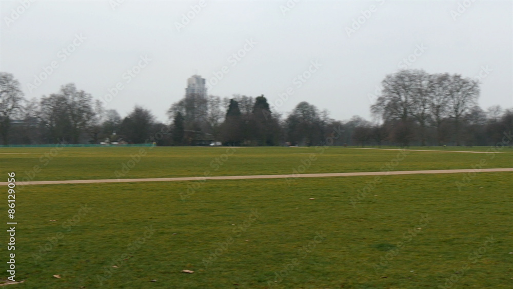 A large green park in London. Seen are green grasses and people walking on the park A large green park in London. Seen are green grasses and people walking on the park