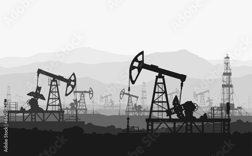 Oil pumps at large oilfield over mountain range.  photo