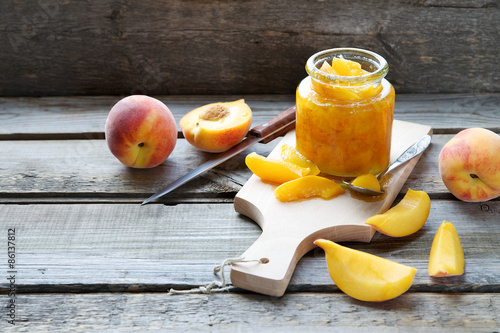 Peach jam in a glass jar on a wooden background 
