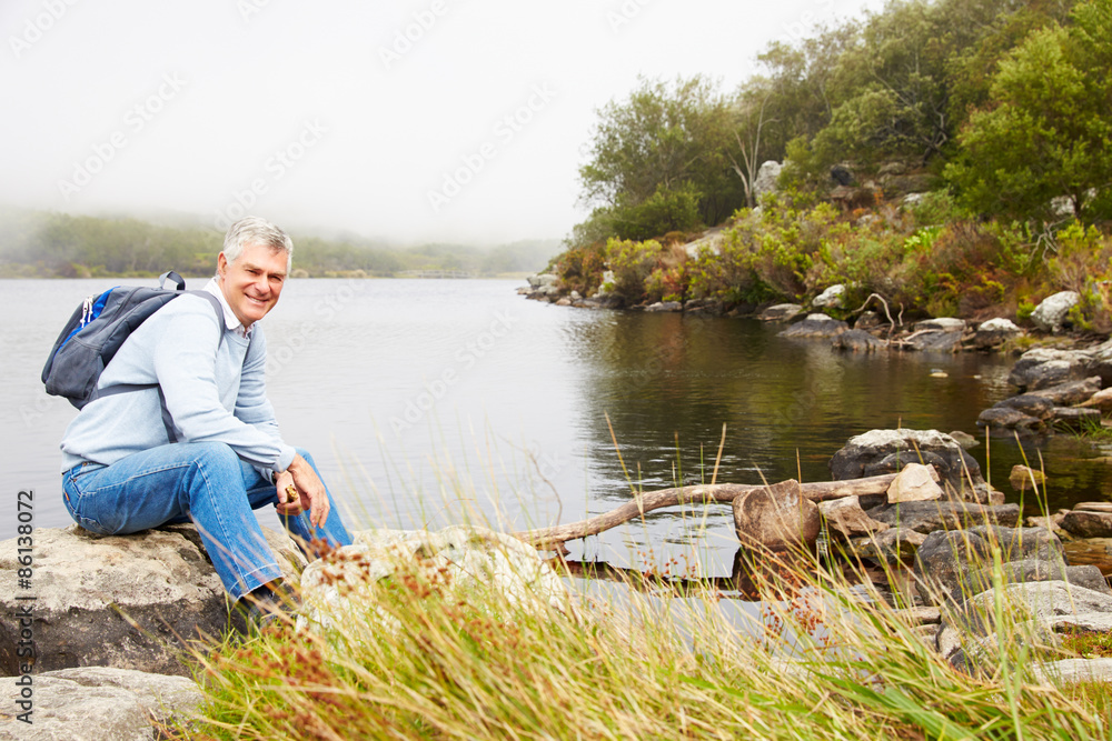 Smiling senior man sitting by a lake Smiling senior man sitting by a lake
