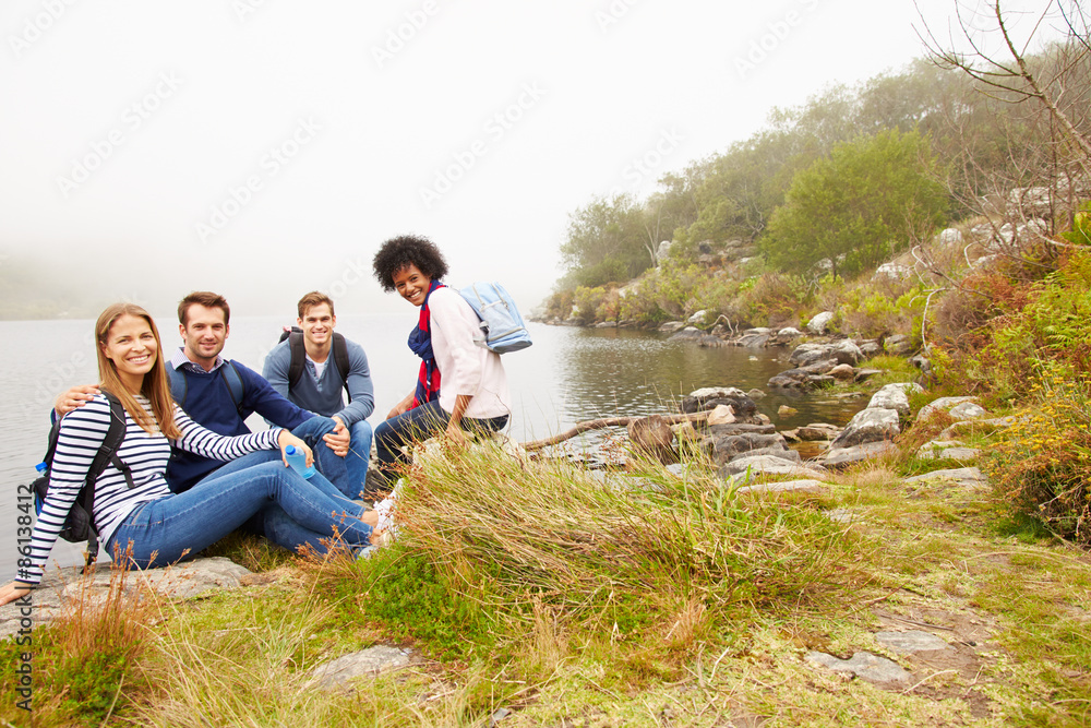 Four friends relaxing by the edge of a lake