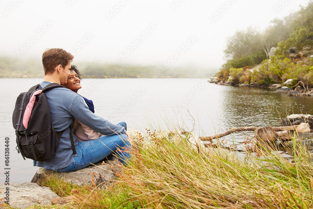 Hiking couple relaxing by the edge of a lake Hiking couple relaxing by the edge of a lake