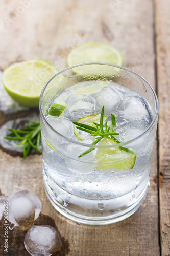 Cocktail with ice and lime slice on wooden background