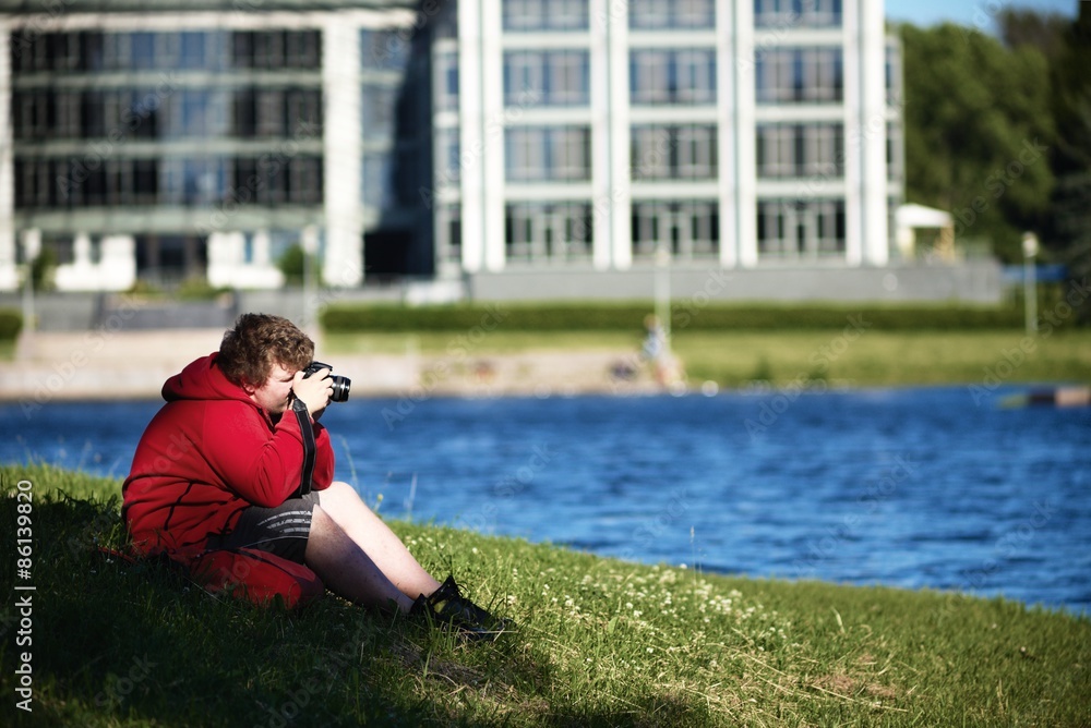 Tourist photographer sits on coast and photographs