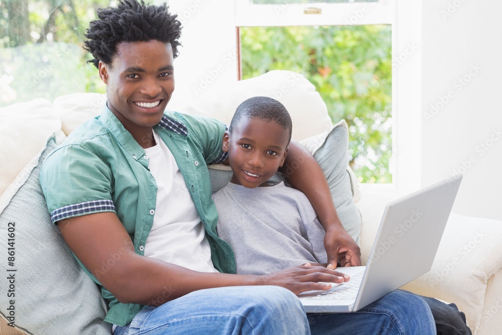 Father and son using laptop on the couch Father and son using laptop on the couch