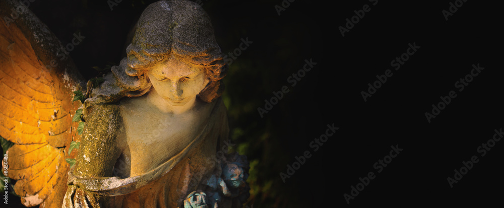 Naklejka premium sculpture of an angel with dark background