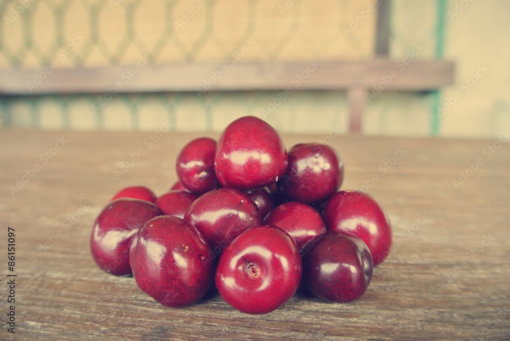 Pile of ripe red fresh cherries on the rustic wooden table, on the terrace of a house. Image edited in faded, washed out, nostalgic, retro style, with Instagram-style filter. Pile of ripe red fresh cherries on the rustic wooden table, on the terrace of a house. Image edited in faded, washed out, nostalgic, retro style, with Instagram-style filter.