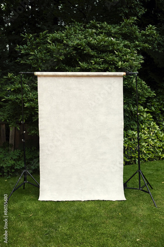 Grey canvas backdrop set up outside in yard with trees behind.