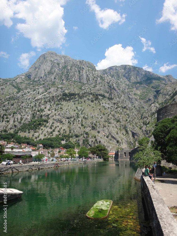 Obraz premium Вид на городскую набережную с туристами и горы в летний солнечный день в южном городке