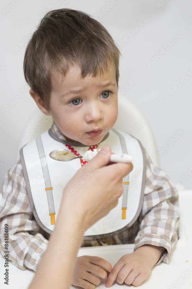 Mother feeding little boy baby food Mother feeding little boy baby food