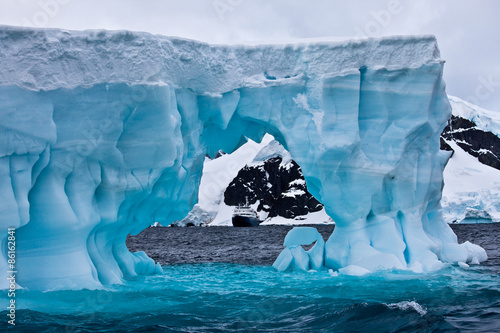 Huge blue iceberg with cruise ship in the distance, Antarctica