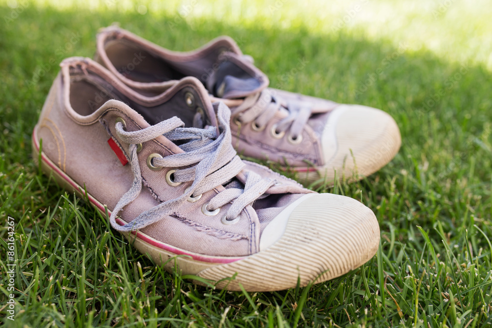 Old worn sneakers on green grass