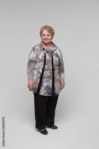 Portrait of an elderly happy woman on a grey background