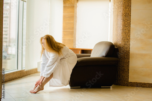 Schilderij op canvas Blonde girl in a white robe caresses your feet