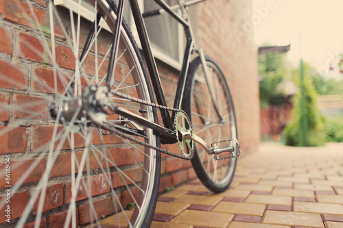 Old style singlespeed bicycle against brick wall, tinted photo