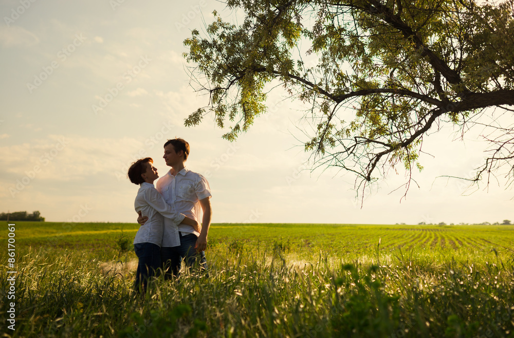 Happy couple standing in the field at the sunset, tinted photo Happy couple standing in the field at the sunset, tinted photo
