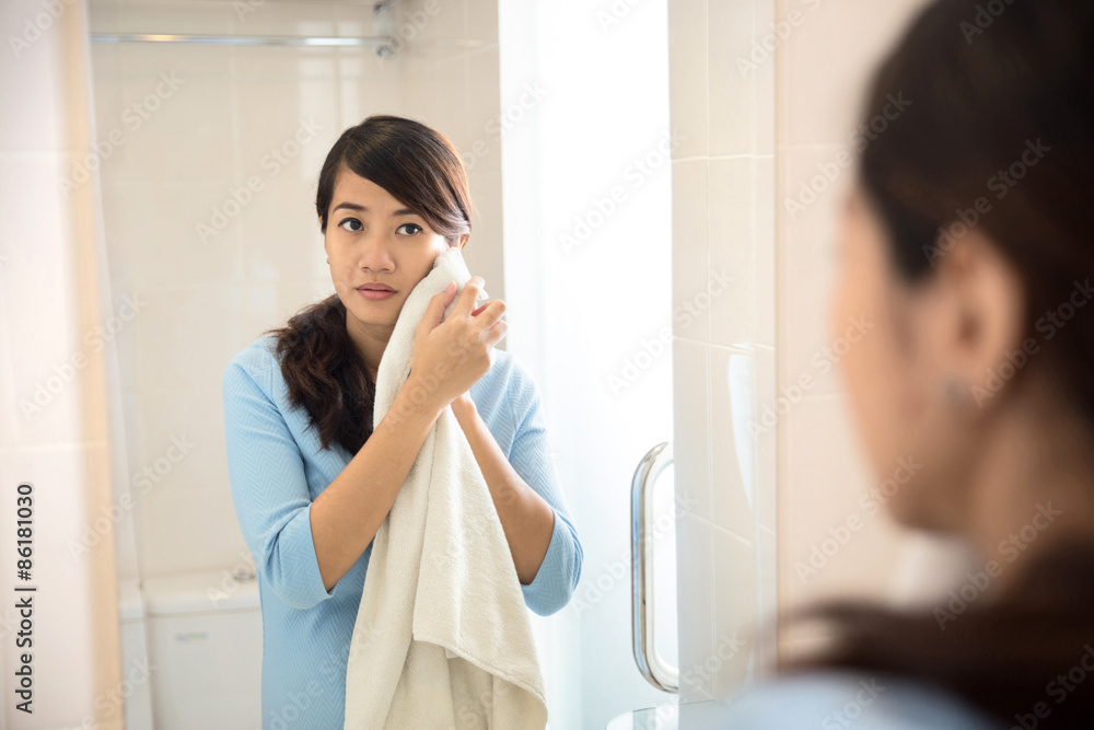 Beautiful asian woman wiping her face with towel, looking at mir Beautiful asian woman wiping her face with towel, looking at mir