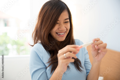 Asian young woman with a testpack in her hand, smiling happily