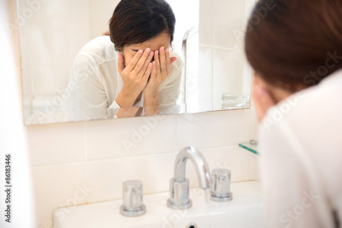 Asian woman washing her face on the sink