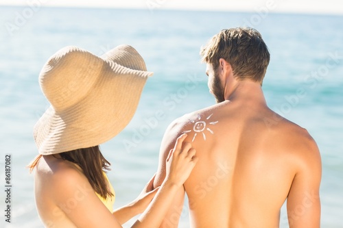 pretty brunette putting sun tan lotion on her boyfriend