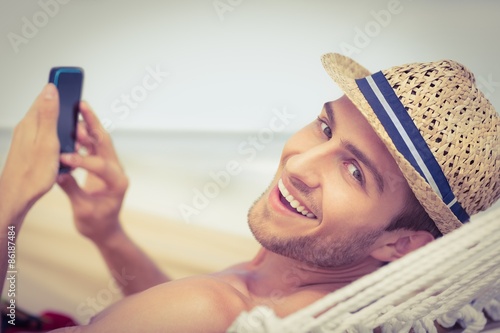 Handsome man texting on the hammock photo
