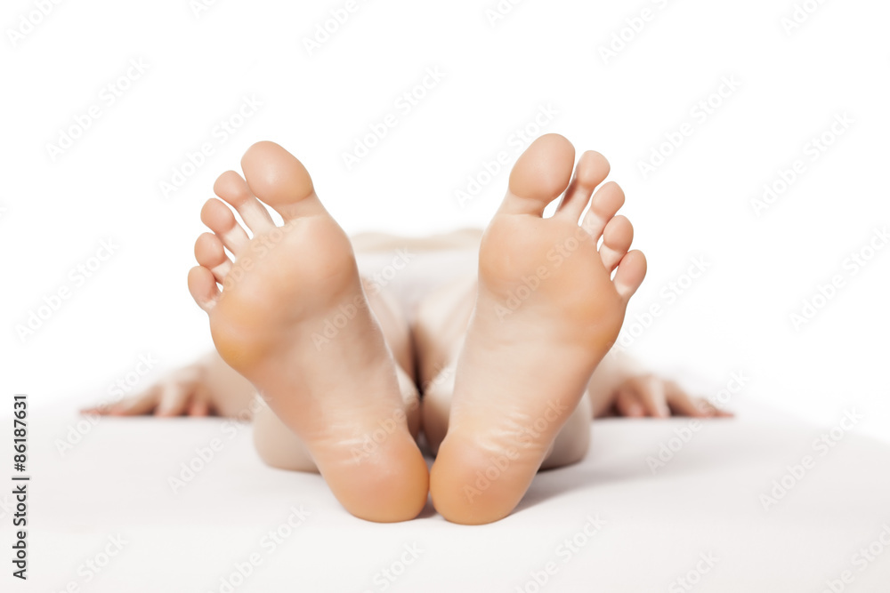 young barefoot woman lying on a bed with the focus on her feet Stock