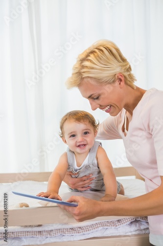 Smiling blonde woman with his son using digital tablet 