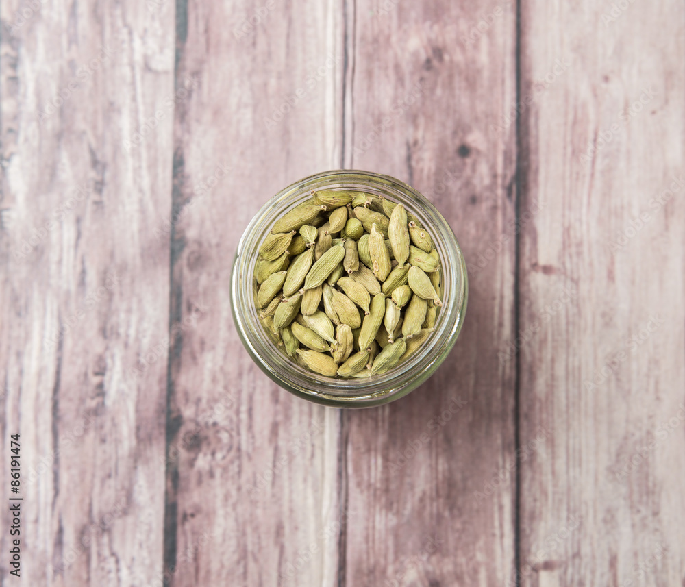 Cardamom spice in a mason jar over weathered wood background Cardamom spice in a mason jar over weathered wood background