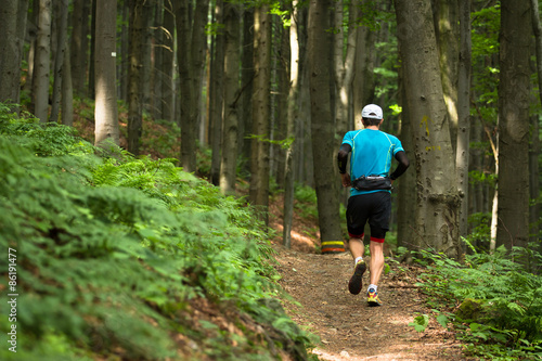 single man with cap running cross country race on the forest trail © lukasx