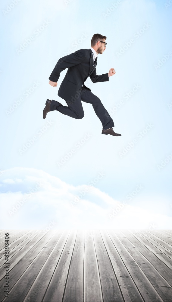 Composite image of geeky young businessman running mid air