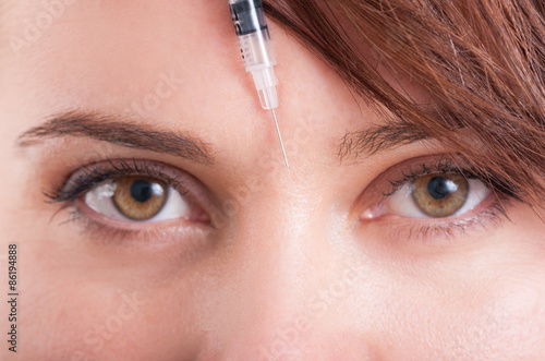 Botox syringe needle between eyes on forehead