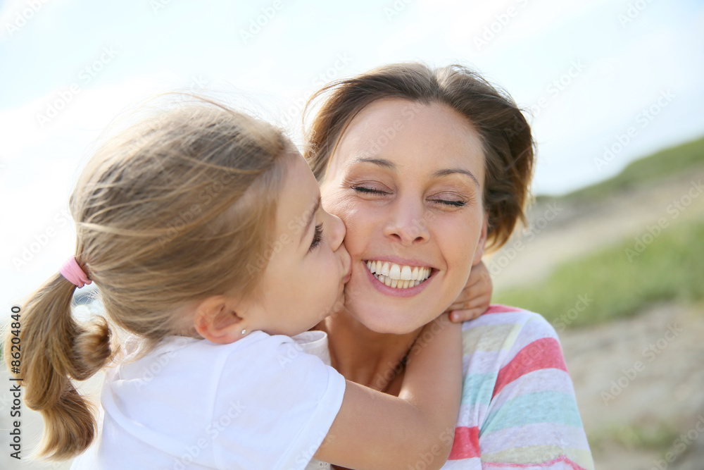 Portrait of cute little girl kissing her mom Portrait of cute little girl kissing her mom