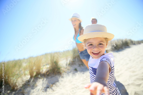 Принти на полотні Little girl pulling parents' arms to run to the beach