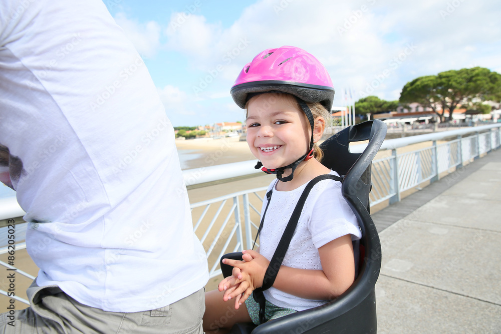 Smiling little girl sitting in child seat on bicycle