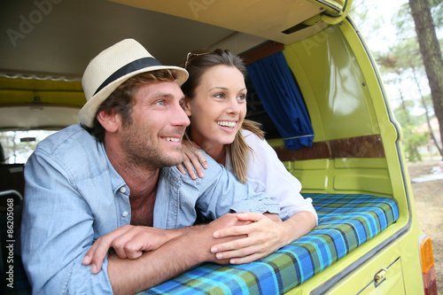 Cheerful young couple laying on a camper van © goodluz