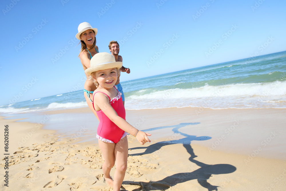 Portrait of little girl running on beach with parents Portrait of little girl running on beach with parents