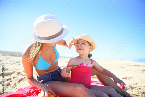 Woman applying sunscreen on daughter's body