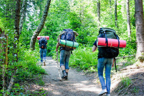 Young people hiking with backpacks. Happy travelers hikers having fun outdoors in forest.