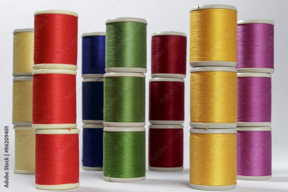 Several columns of bobbins of cotton thread for sewing machines with the colors of rainbow Several columns of bobbins of cotton thread for sewing machines with the colors of rainbow