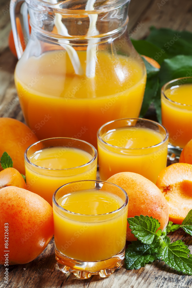 Fresh apricot juice and apricots with mint on old wooden table,