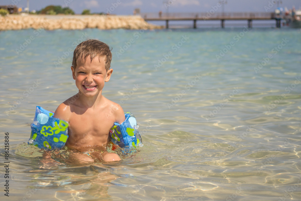 Little boy in the sea with inflatable oversleeves for swimming Little boy in the sea with inflatable oversleeves for swimming